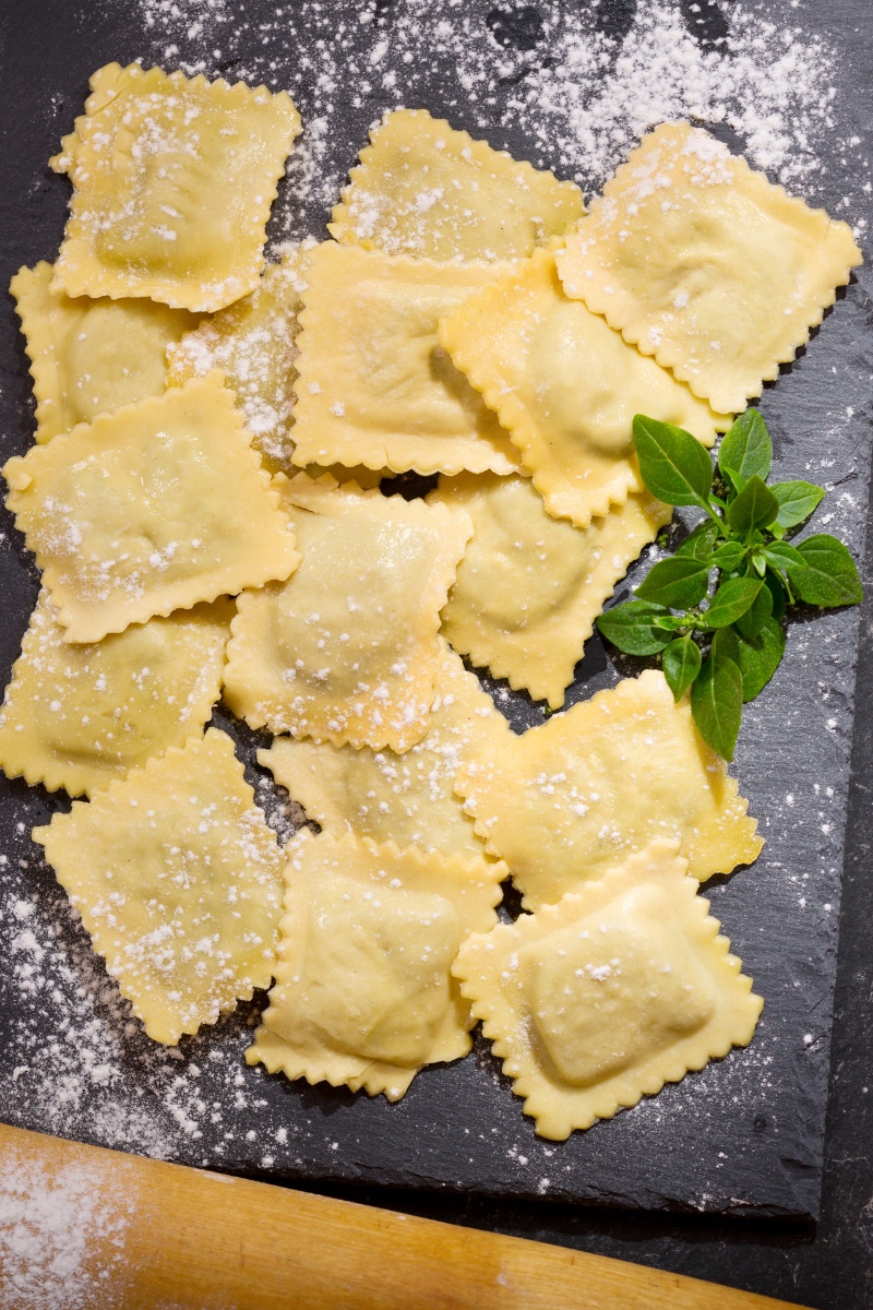 several fresh ravioli on a counter next to a rolling pin