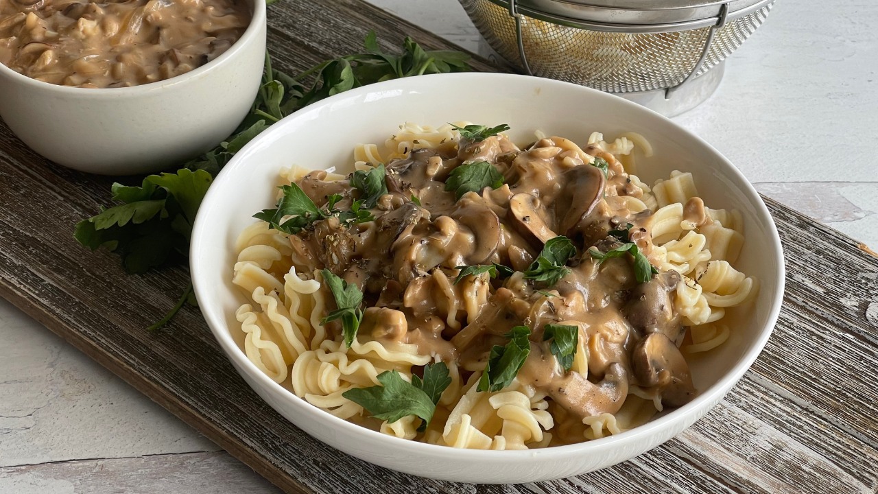 bowl of noodles topped with a stroganoff sauce and parsley leaves