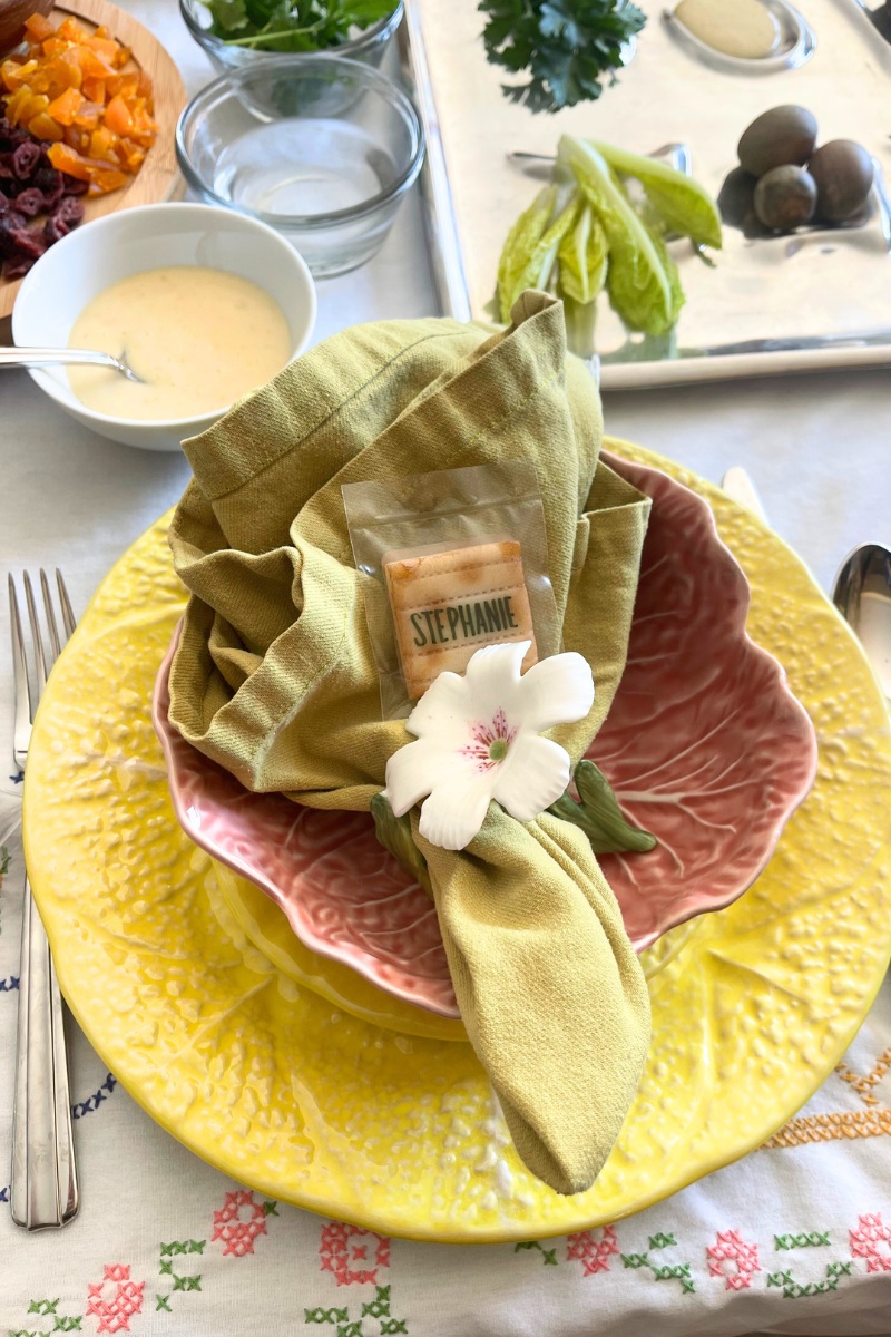 yellow plate with a pink bowl on top and a napkin with a flower napkin ring