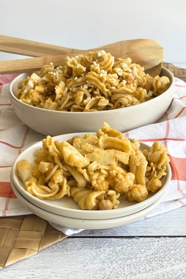 Bowl of pasta salad with a serving of it on a plate on a counter