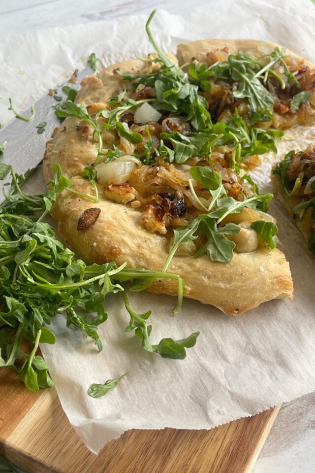 three quarters of a pizza on parchment paper on top of a cutting board