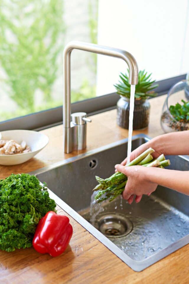 A woman washing asparagus in the sink