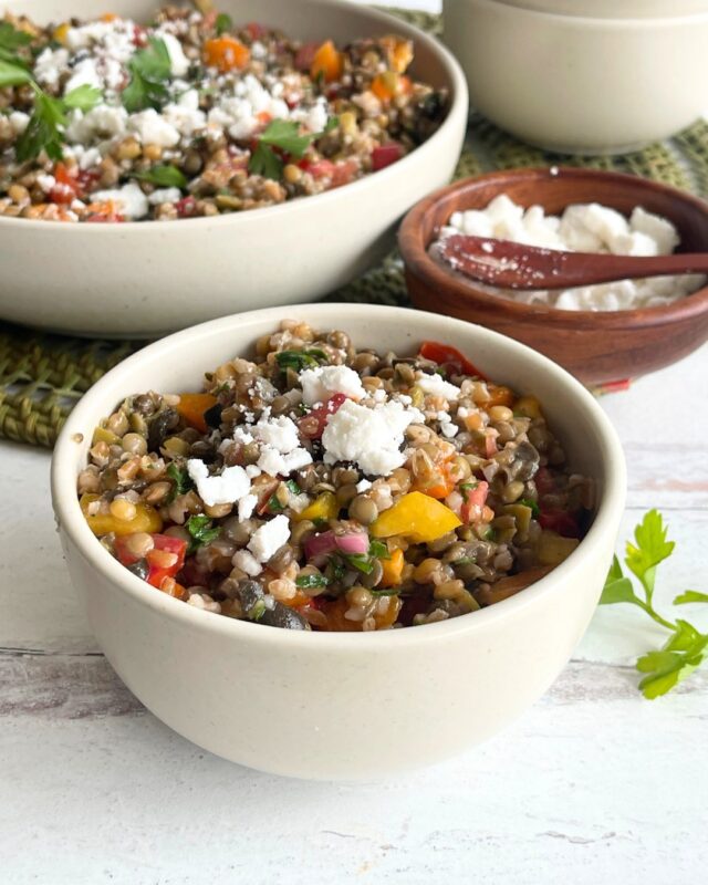 close up of a bowl of lentil salad in front of two other bowls