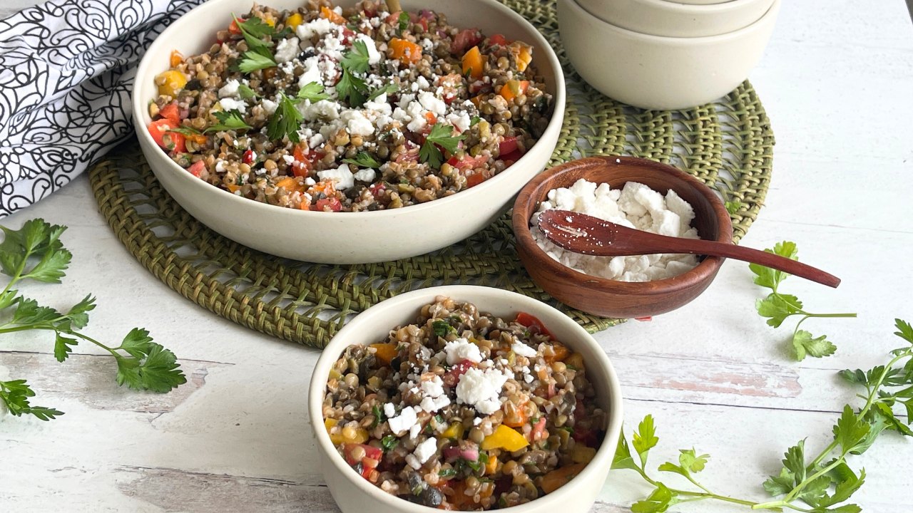 two bowls of lentil tabbouleh salad on a green placemat next to a bowl of feta cheese