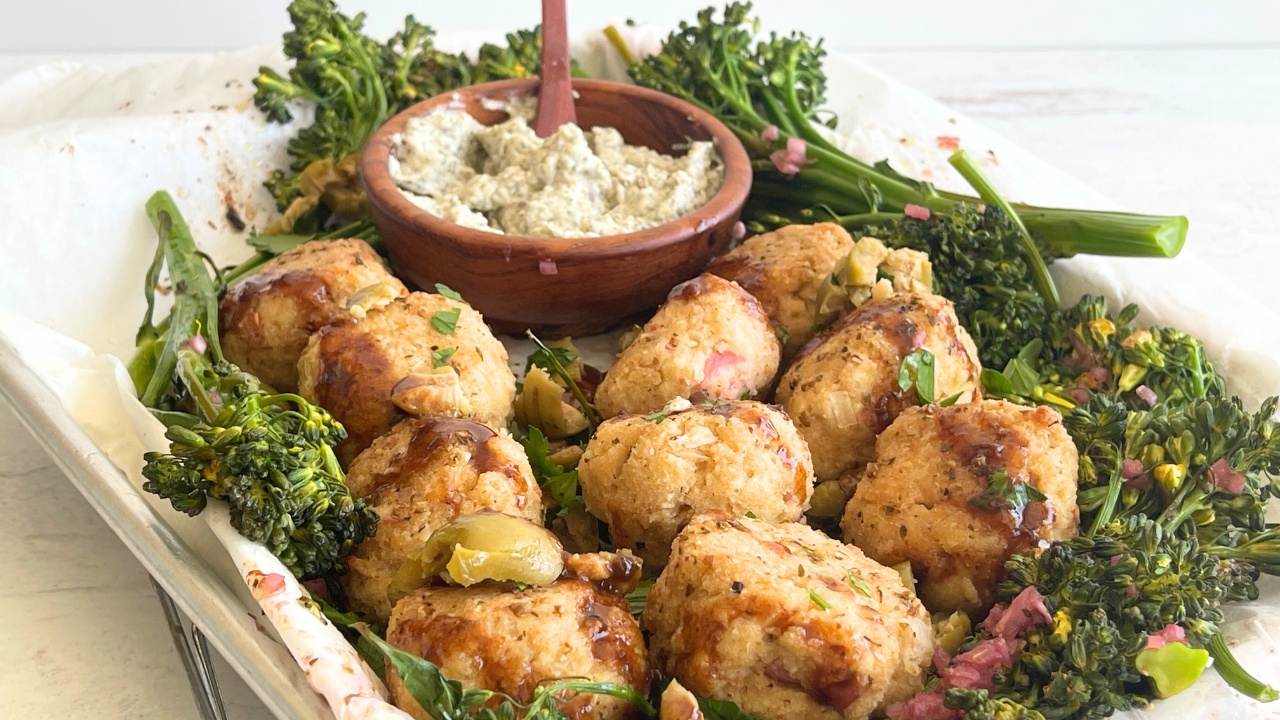 sheet pan with tofu meatballs next to a bowl of garlic sauce