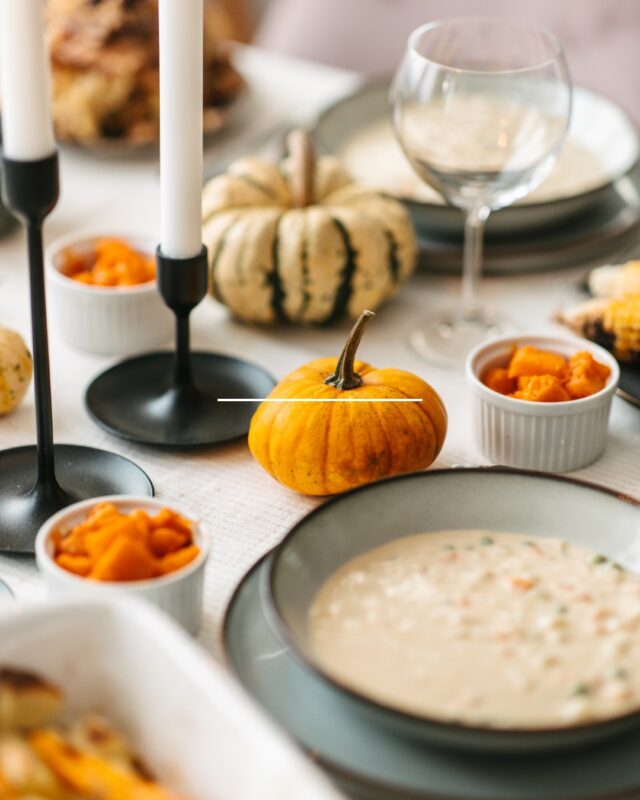 dinner table decorated with pumpkins and set with bowls of soup