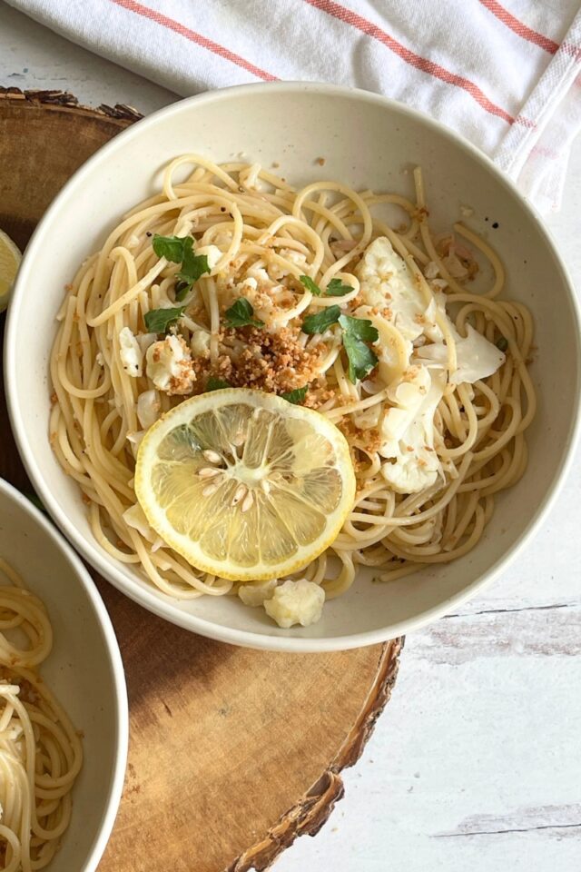 bowl of pasta next to a white and orange striped dish towel