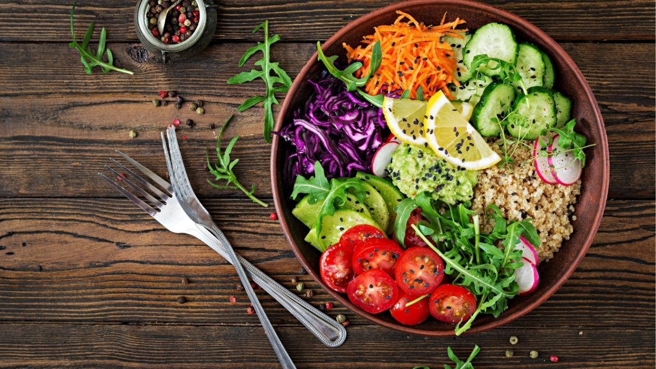 bowl of vegetables on a wood table with two forks beside it