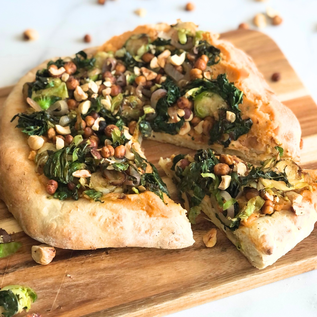 A whole pizza on a cutting board, sliced into pieces