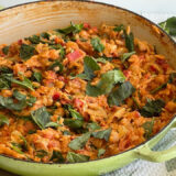 green round Dutch oven with orzo, tomatoes and vegetables on a countertop