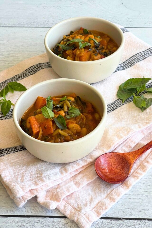 two bowls of soup on black and white dish towel next to a wood spoon