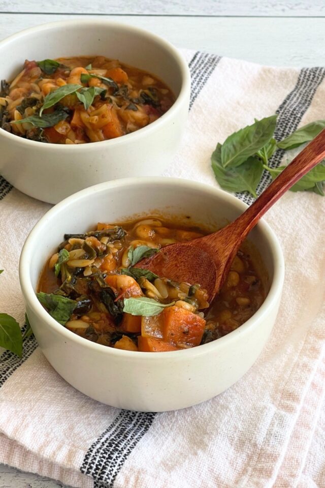 two bowls of soup, one with a wood spoon in it on a black and white dish towel