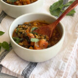 bowl of soup with a wooden spoon in it on a black and white dish towel