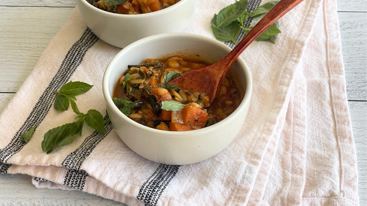 bowl of soup with a wooden spoon in it on a black and white dish towel