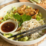 rice noodles, vegetables and tempeh in a bowl with chopsticks