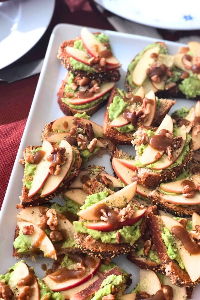 slices of crostini with apples and walnuts on a white platter