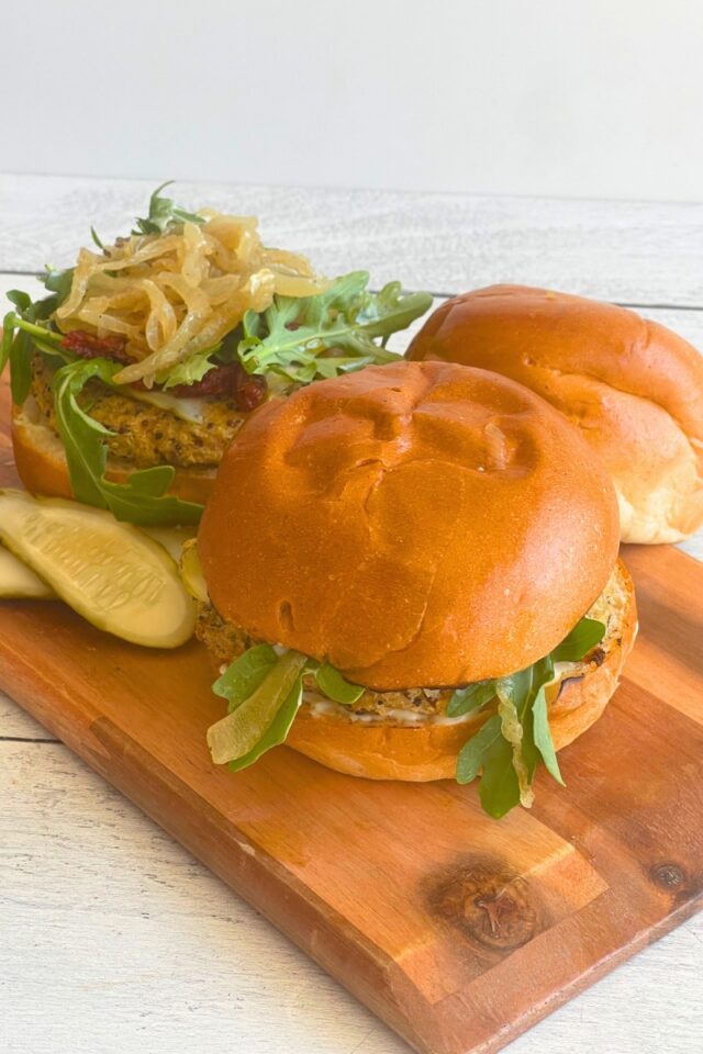 two burgers on a cutting board set on a marble countertop