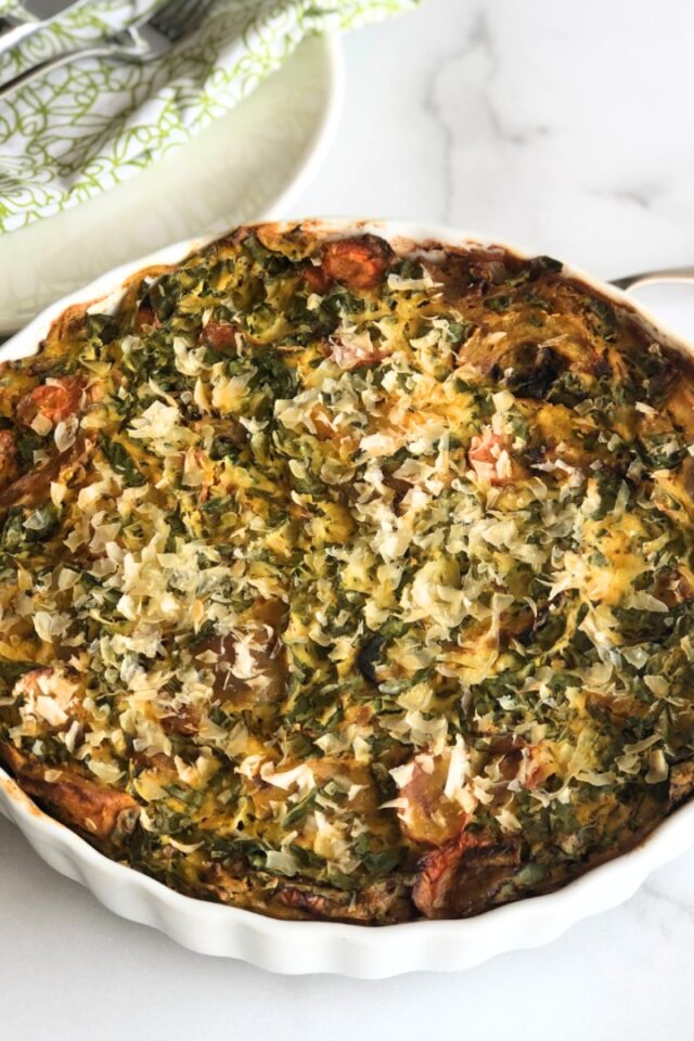 frittata in a white ceramic scalloped dish on a white countertop