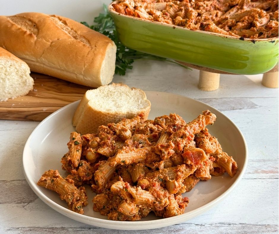 plate with penne pasta and marinara sauce on it and a slice of bread