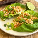 Lettuce wraps on a white plate on top of a wicker placemat