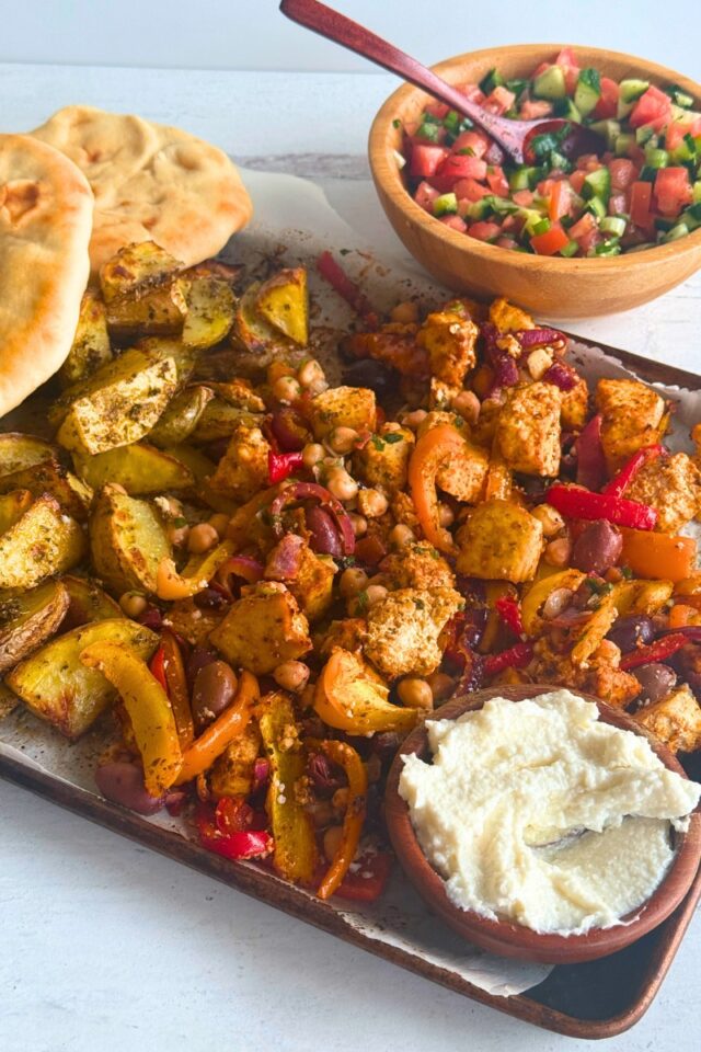 Sheet pan with tofu, vegetables pita and a bowl of garlic sauce