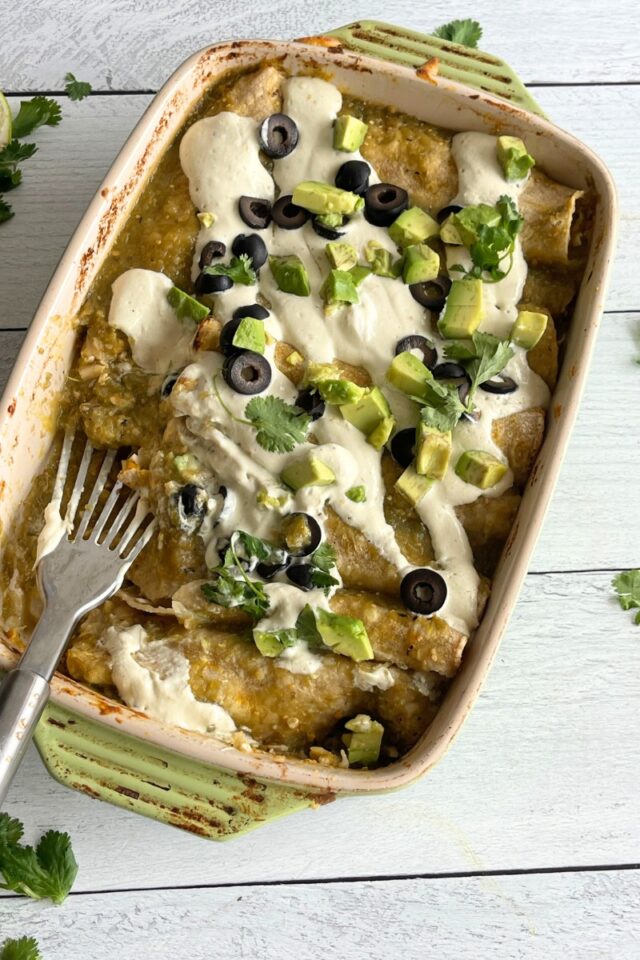 casserole dish of enchiladas with a metal spatula laying inside