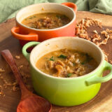 small green bowl of soup on a round wooden cutting board