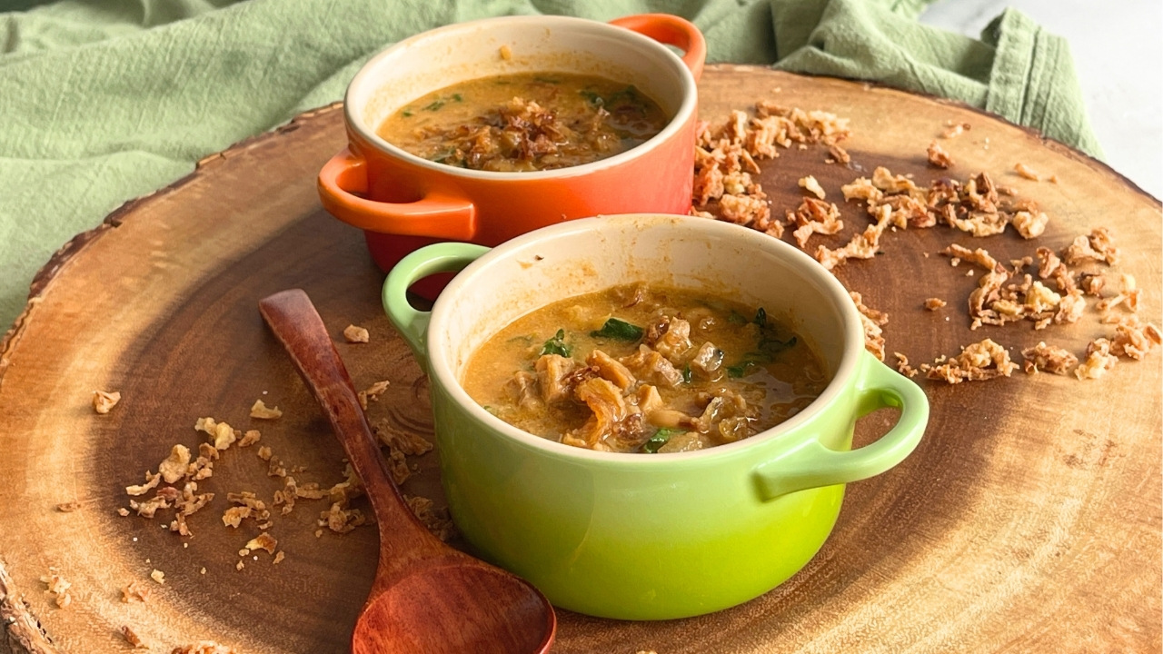 small green bowl of soup on a round wooden cutting board