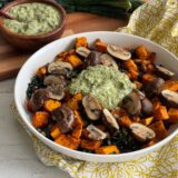 bowl of sweet potatoes and mushrooms with a dollop of green sauce on top next to a smaller bowl of the same green sauce